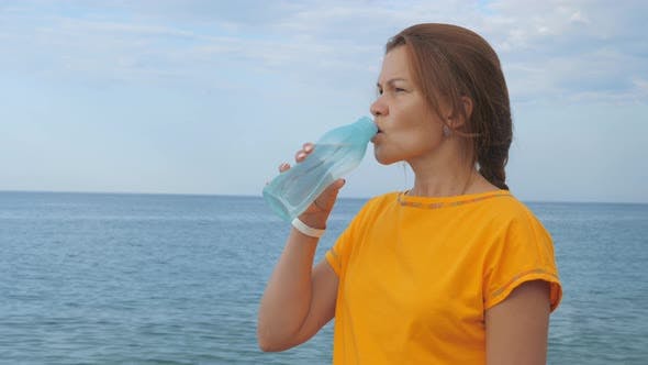 mulher bebendo agua na praia